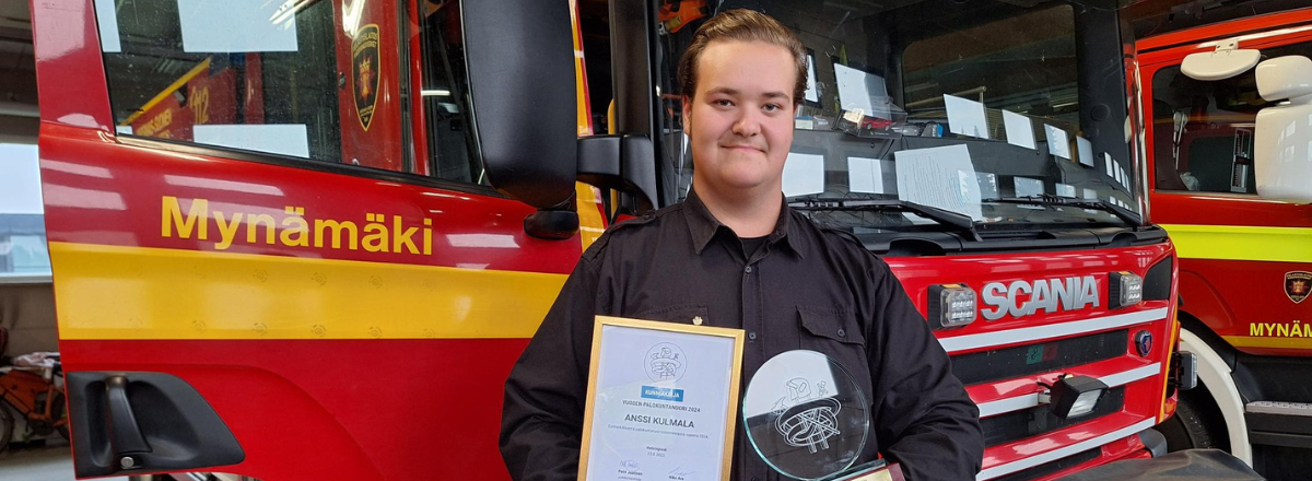 Vuoden palokuntanuori Anssi Kulmala poseeraa paloauton edessä